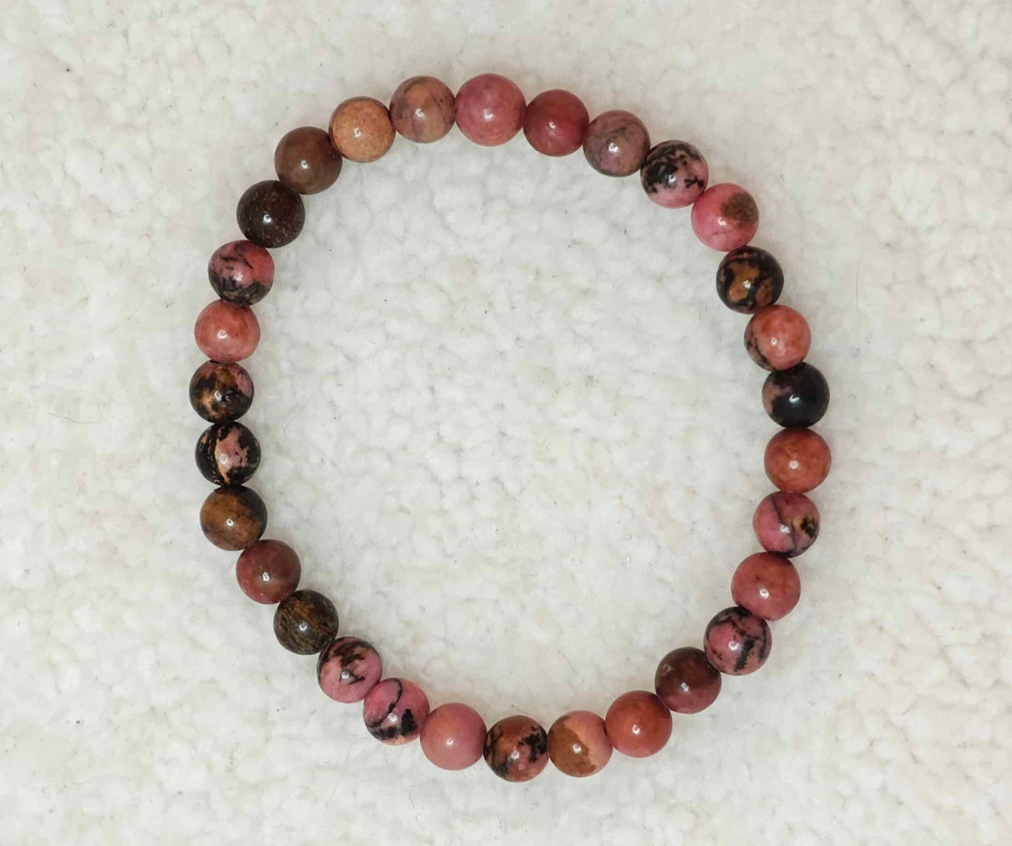 Pierre : Rhodonite - Qualité : AB - Origine : Brésil Taille de perle : 6mm - Forme : Boule Le produit que tu recevras peut différer de la photo de présentation, car chaque pierre naturelle est unique !